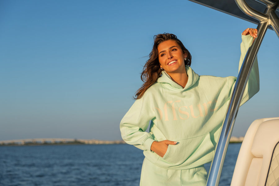Friend laughing on a boat at sunset in the Offsure Print Pullover in Sea Glass