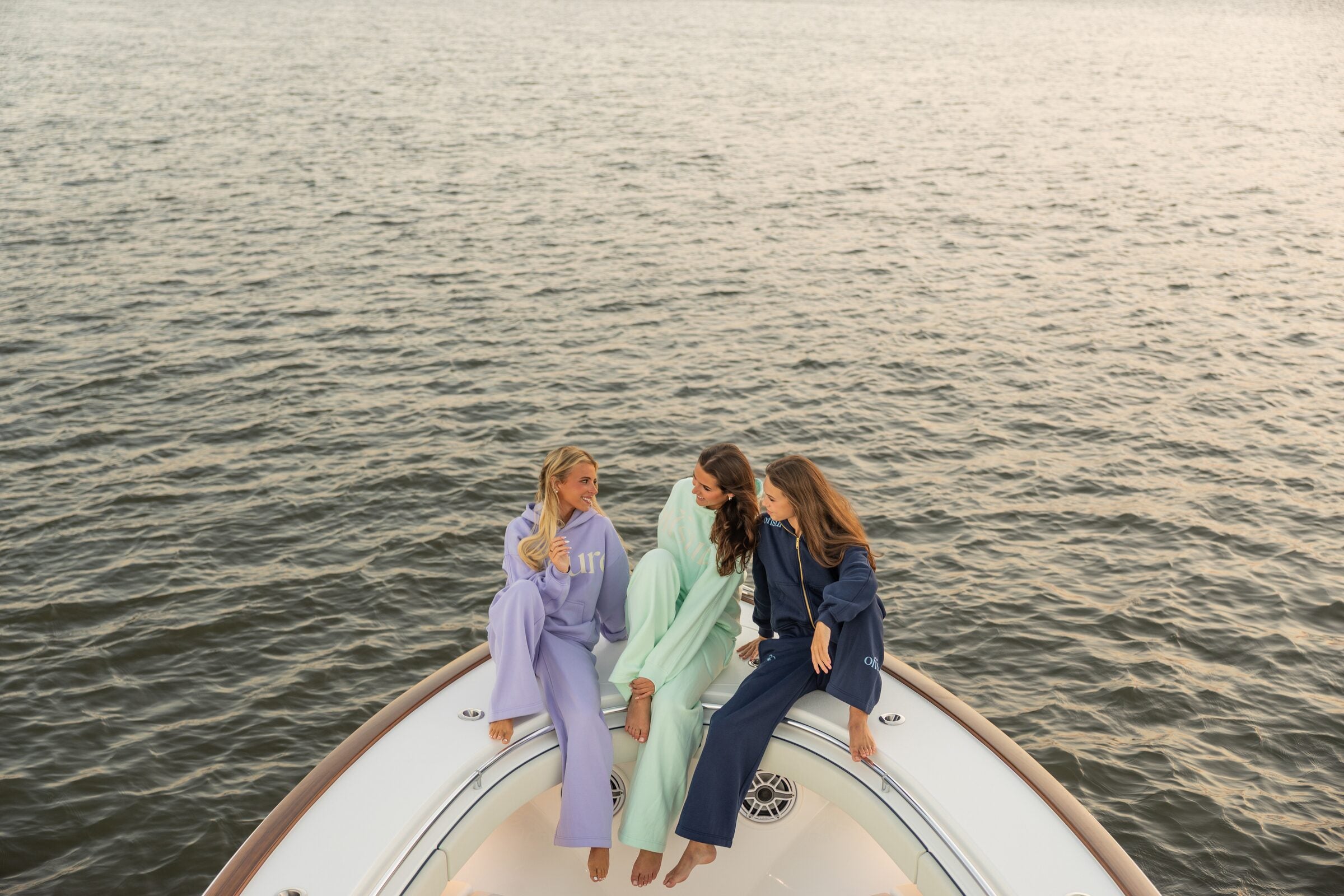 Overhead of three friends on a boat bow in matching Offsure sets