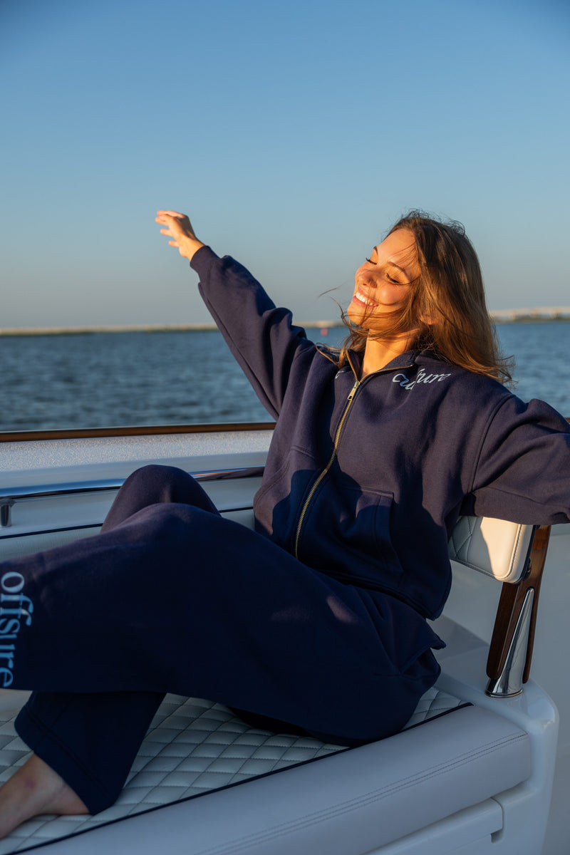 Offsure Full-Zip Hoodie and Graphic Pant in Navy Coast, seated on the boat